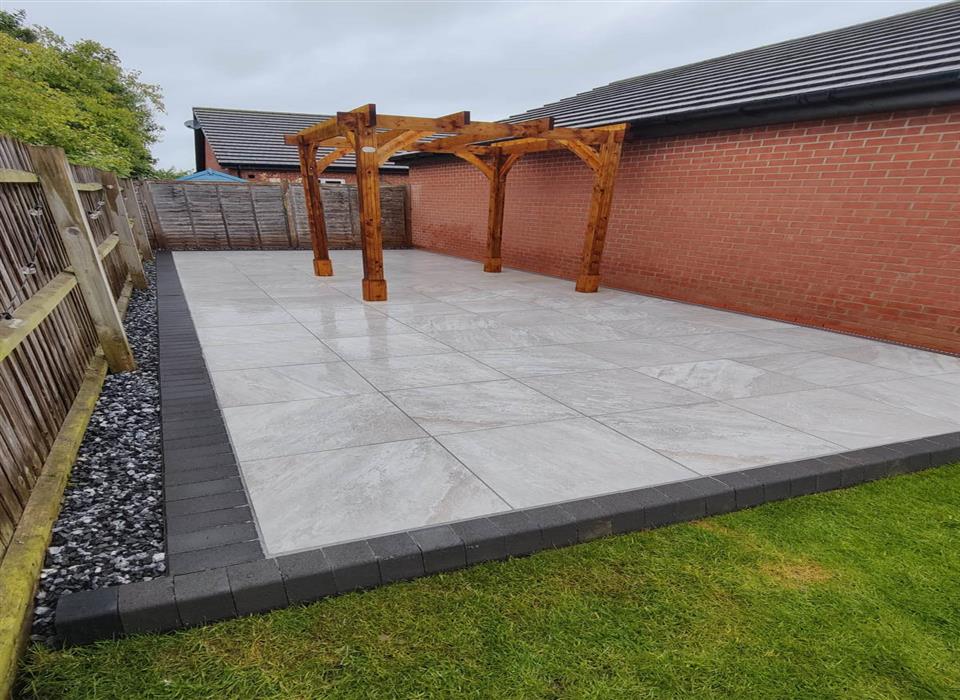 Wooden garden pergola with porcelain patio and integrated rainwater drainage system in Bedford