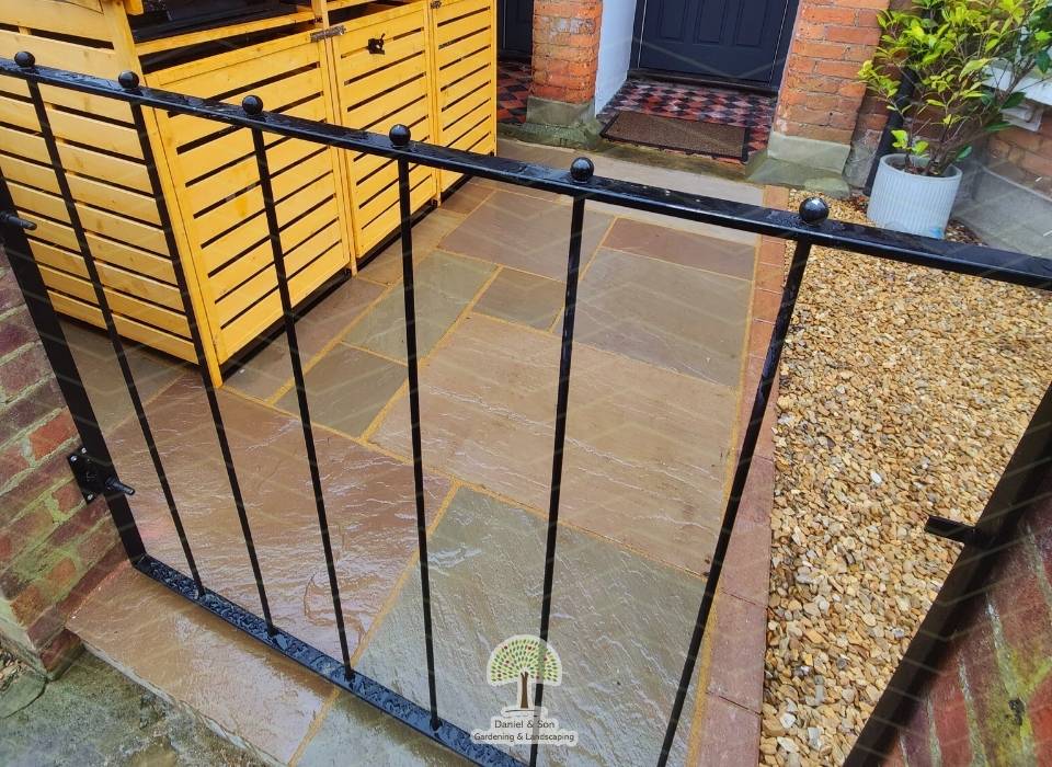 Front garden makeover featuring Sunset Buff sandstone paving and a sleek black metal gate, enhancing curb appeal with a modern and secure design.